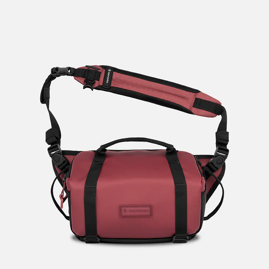 burgandy camera bag with black straps on a white background
