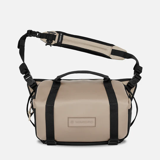 Beige and black bag with a strap on a white background