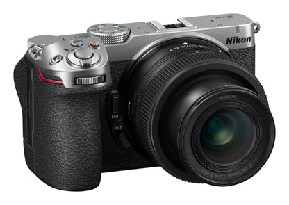 A Nikon mirrorless camera with a silver top plate, black textured grip, and attached black Nikkor lens, shown on a plain white background.